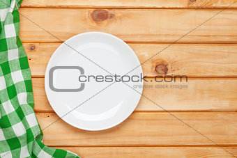 Empty plate and towel over wooden table background