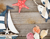 Toy sailboat and fish with seashells and starfish on a wooden ba