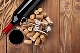 Glass of red wine, bottle and corkscrew on rustic wooden table