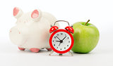 Fresh green apple with alarm clock and piggy bank