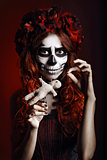 Young woman with muertos makeup (sugar skull) piercing voodoo doll