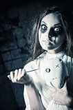 Horror style shot: scary crazy girl with moppet doll and needle in hands