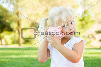 Little Girl Having Fun with Her Piggy Bank Outside