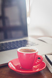Red coffee cup with notepad and laptop