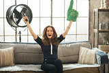 Football fan woman watching tv in loft apartment and rejoicing