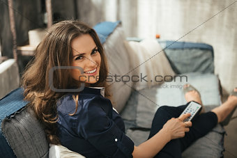 Woman with TV remote control  relaxing on sofa in loft apartment