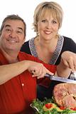 happy couple carving a ham isolated on white