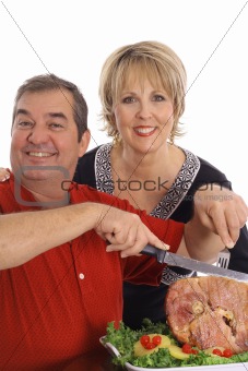 couple carving a ham isolated on white