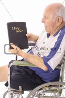 elderly man in wheelchair reading the bible isolated on white