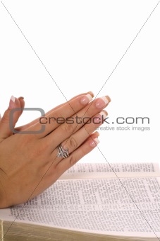 shot of praying hands on scripture
