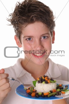 shot of a young boy eating healthy rice, beans & veggies vertical