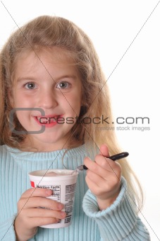 shot of a happy little girl eating yogurt vertical
