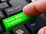 Pressing Green Button Bank Wire Transfer on Black Keyboard.