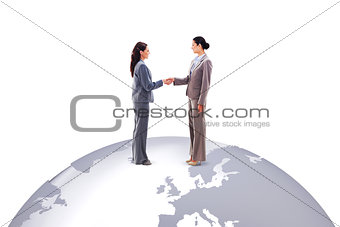 Composite image of two businesswomen shaking hands