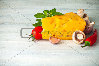 Part cheese with vegetables and basil on wooden board
