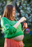Pregnant woman blowing bubbles outdoor