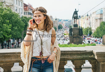 Hippie woman in bohemian clothes talking cell phone in Prague