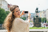 Trendy hippie woman tourist taking photo on mobile in Prague