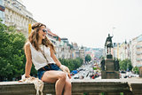Happy woman in boho chic clothes relaxing on parapet, Prague