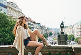 Trendy hippie woman sitting on parapet on Wenceslas Square