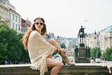 Woman in boho chic clothes relaxing on stone parapet in Prague