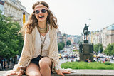 Hippy-looking woman tourist sitting on stone parapet in Prague
