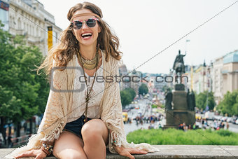 Hippy-looking woman tourist sitting on stone parapet in Prague