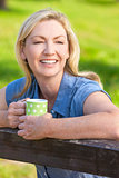 Woman Resting on Fence Drinking Tea or Coffee