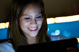 Latina Teenager Using Social Media On Tablet PC At Night