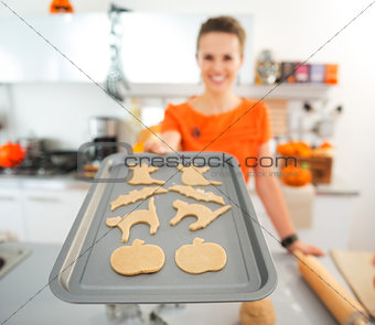 Closeup on woman holding tray of uncooked Halloween biscuits