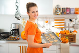 Happy woman holding tray of uncooked Halloween biscuits