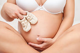 Pregnant woman holding a pair of tiny shoes