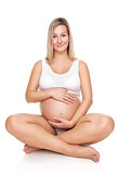 Portrait of a pregnant woman sitting on floor and holding belly