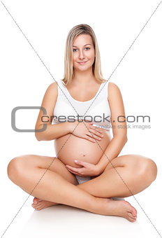Portrait of a pregnant woman sitting on floor and holding belly