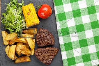 Steak with grilled potato, corn, salad and tomato