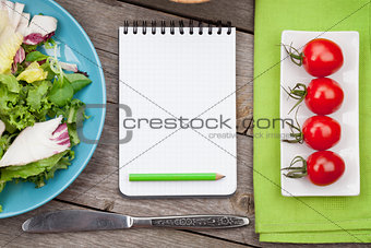 Fresh healthy salad, tomatoes and notepad for copy space