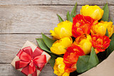 Colorful tulips and gift box on wooden table