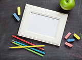 Photo frame and school supplies on blackboard background