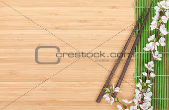 Chopsticks and sakura branch over bamboo mat