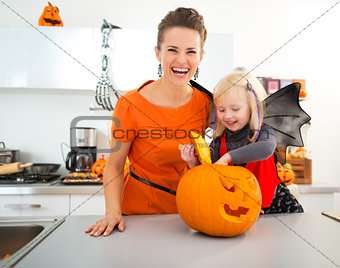 Halloween dressed girl with mother preparing Jack-O-Lantern