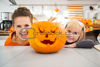 Funny mother with daughter in Halloween decorated kitchen