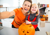 Halloween dressed girl and mother making selfie in kitchen