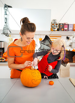 Happy mother with daughter creating Jack-O-Lantern on Halloween
