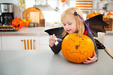 Halloween dressed girl creating big pumpkin Jack-O-Lantern