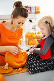Mother with daughter carving Jack-O-Lantern for Halloween party