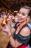 Beautiful young woman in traditional Dirndl eating Oktoberfest Pretzel, multi-racial Asian, from the Philippines and Caucasian mix