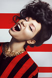 Beautiful screaming woman with curly hair on a striped white red background
