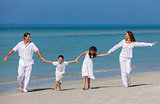 Mother, Father and Children Family Running Having Fun At Beach
