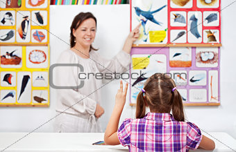 Young girl in elementary science class raising hand
