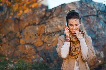 Woman talking cell phone while walking in autumn outdoors
